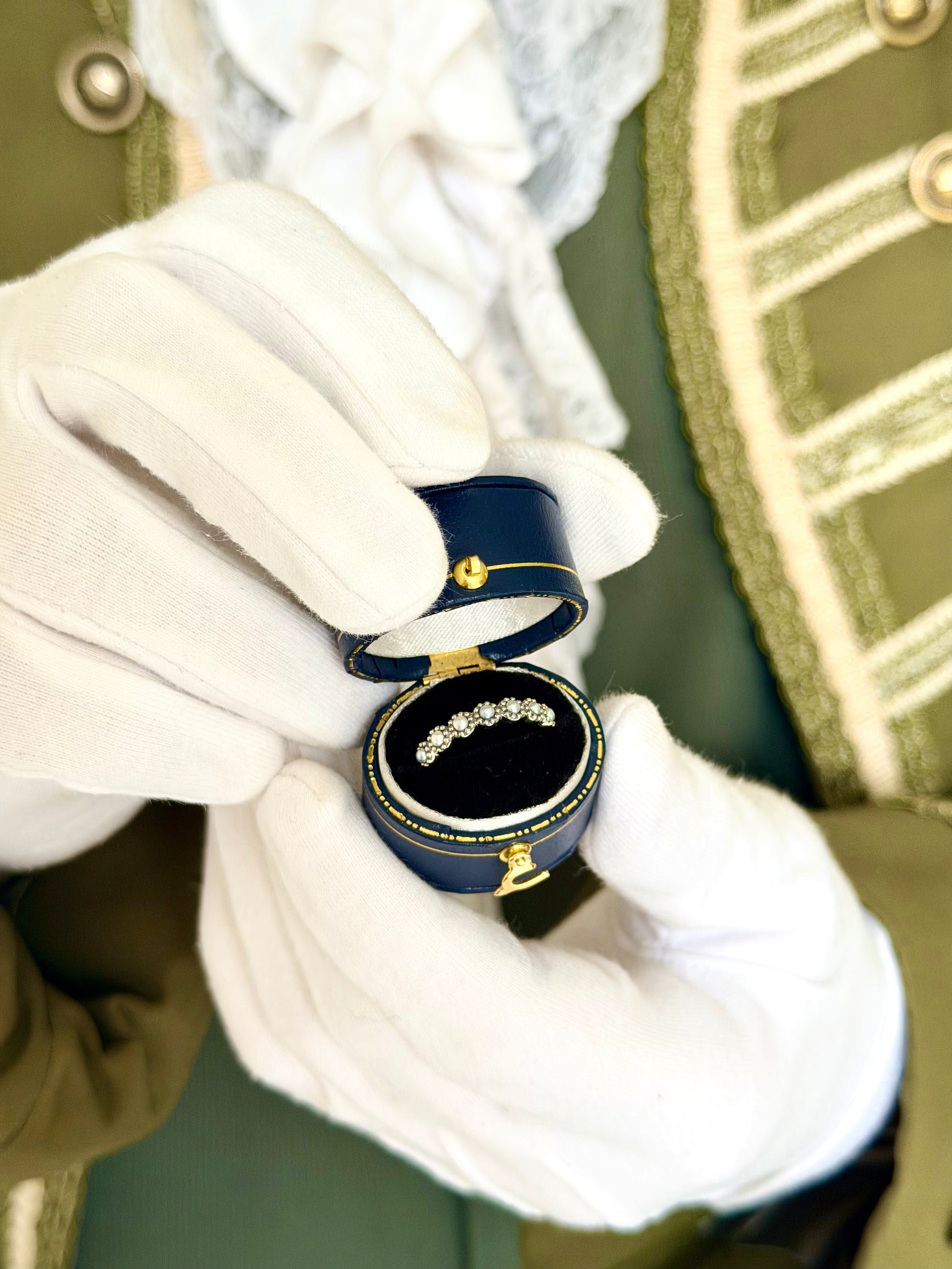 Silver Daisy Chain pearl ring in a navy antique ring box held by white-gloved hands, vintage-inspired stacking ring