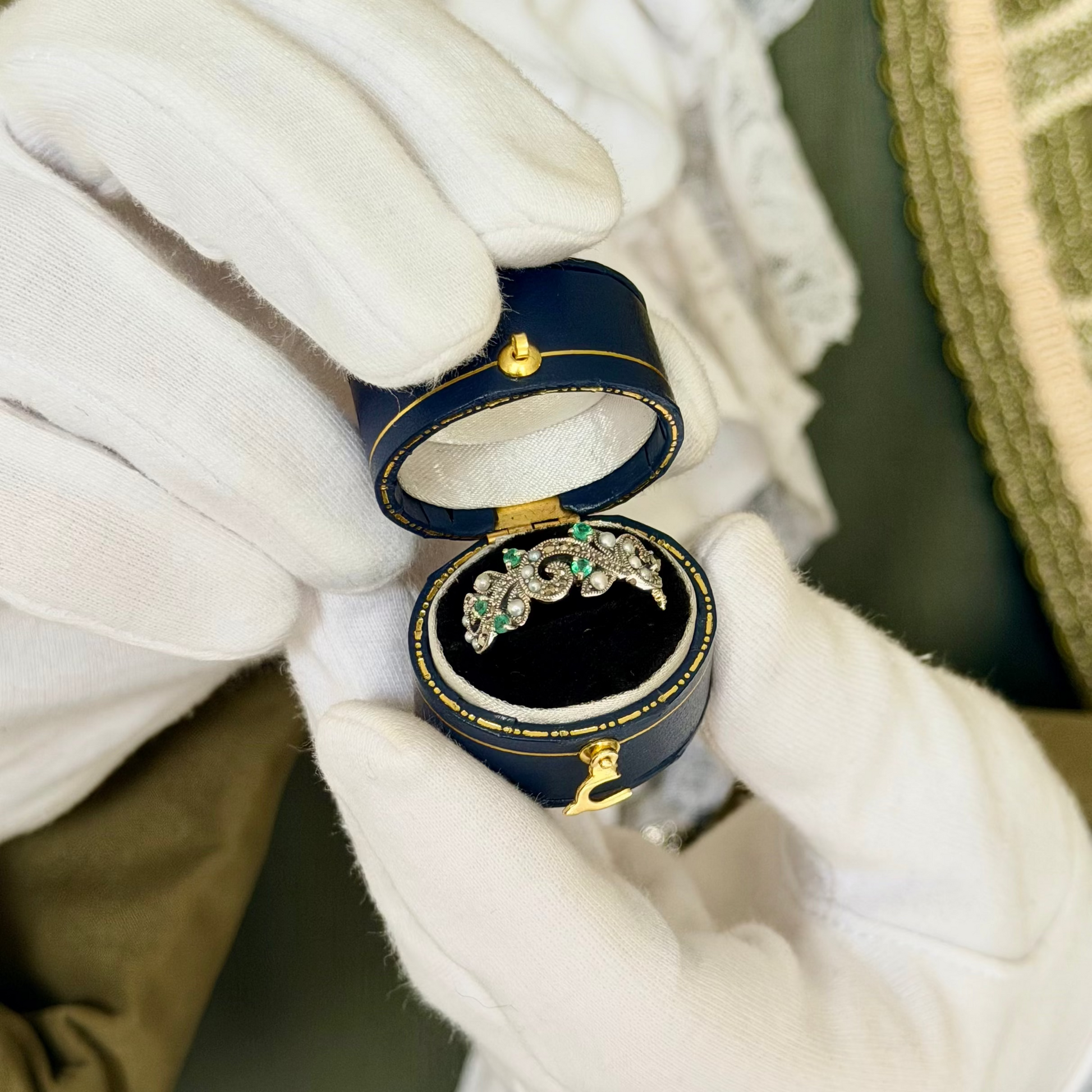 Emerald Sapling emerald, pearl and silver filigree ring in a navy antique ring box held by white-gloved hands