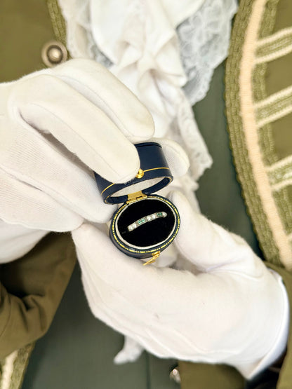 Silver Emerald Gaze emerald and pearl eternity ring in a navy antique ring box held by white-gloved hands