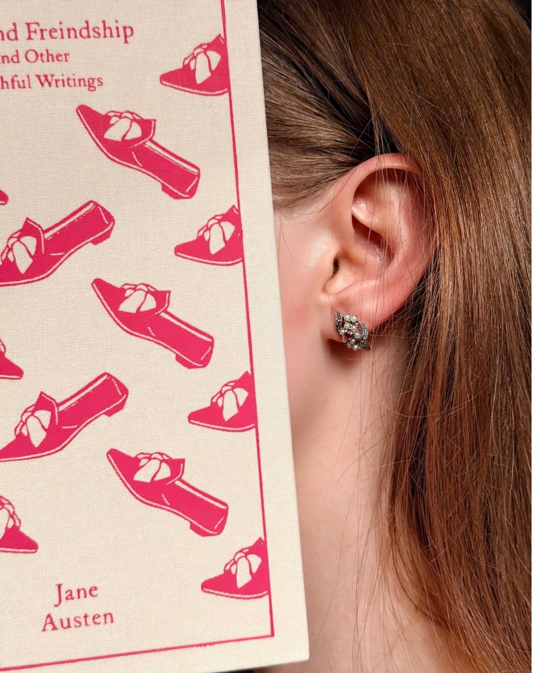Model wearing Ruby Flower ruby and pearl 925 silver stud earrings beside a Jane Austen book, vintage-style studs