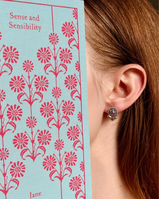 Model wearing Mirror Studs blue topaz and 925 silver stud earrings beside a Sense and Sensibility book, antique-style earrings