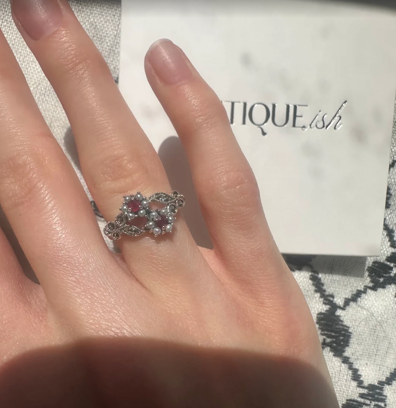 A finger wearing the Toi-Et-Moi ruby ring in the sunlight, victorian inspired design.