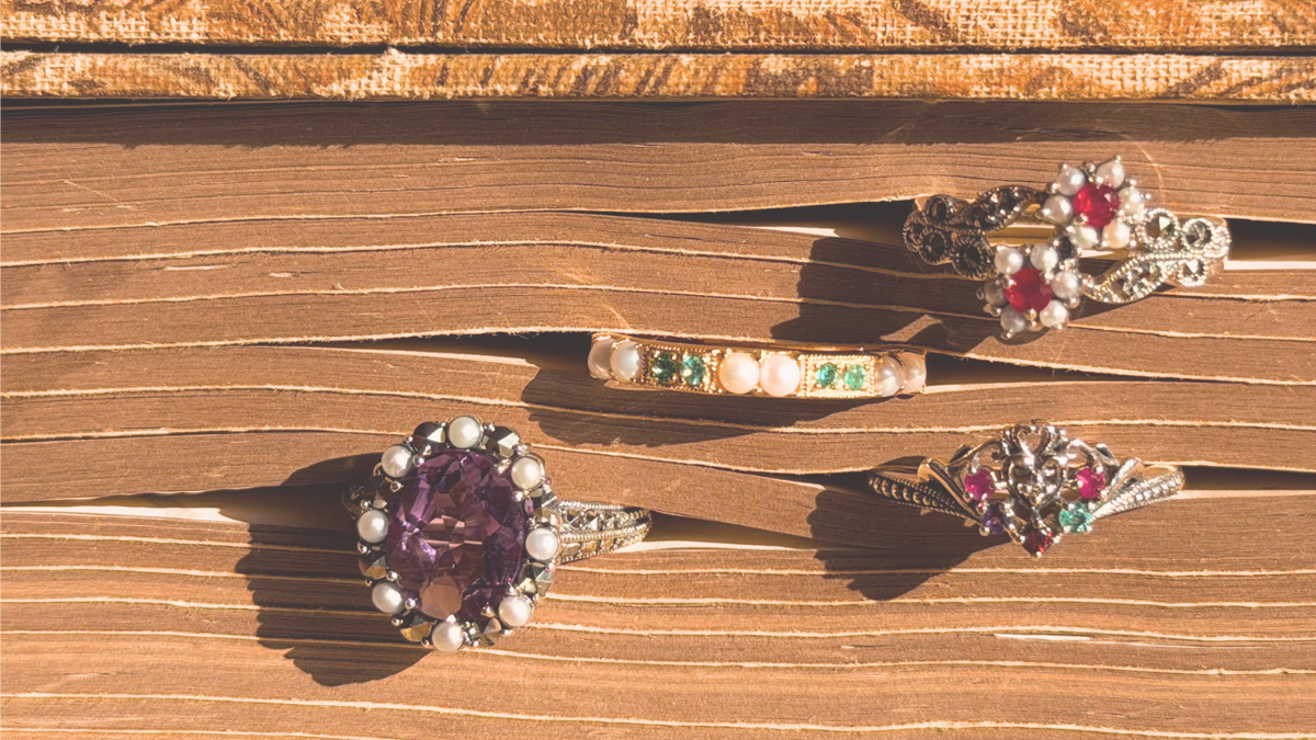 Vintage-inspired sterling silver gemstone rings with purple, red and green stones and pearls on antique book pages